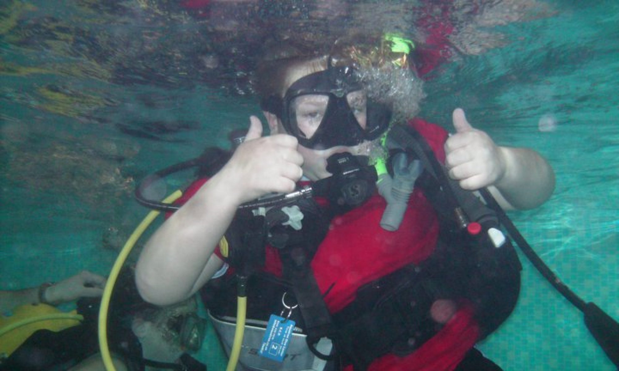 A 6th East Kilbride Scout giving a thumbs-up gesture while practicing underwater skills during a Scuba diving taster session.